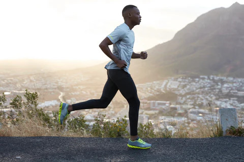 man running on road with mountain city background