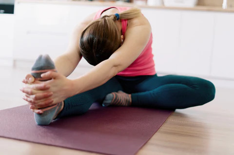 woman stetching on the ground hands pulling on foot